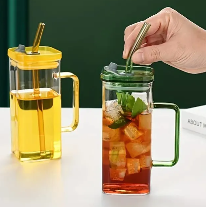 Two glass mugs with metal straws, one filled with yellow liquid and the other with iced tea.