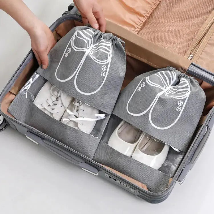 Gray shoe bags with white graphics being used to pack shoes into asuitcase. mypickmart