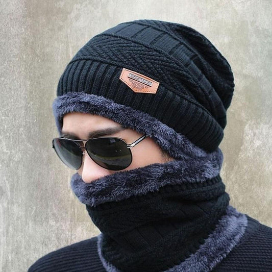 Person wearing a black knit beanie and matching scarf with a textured background