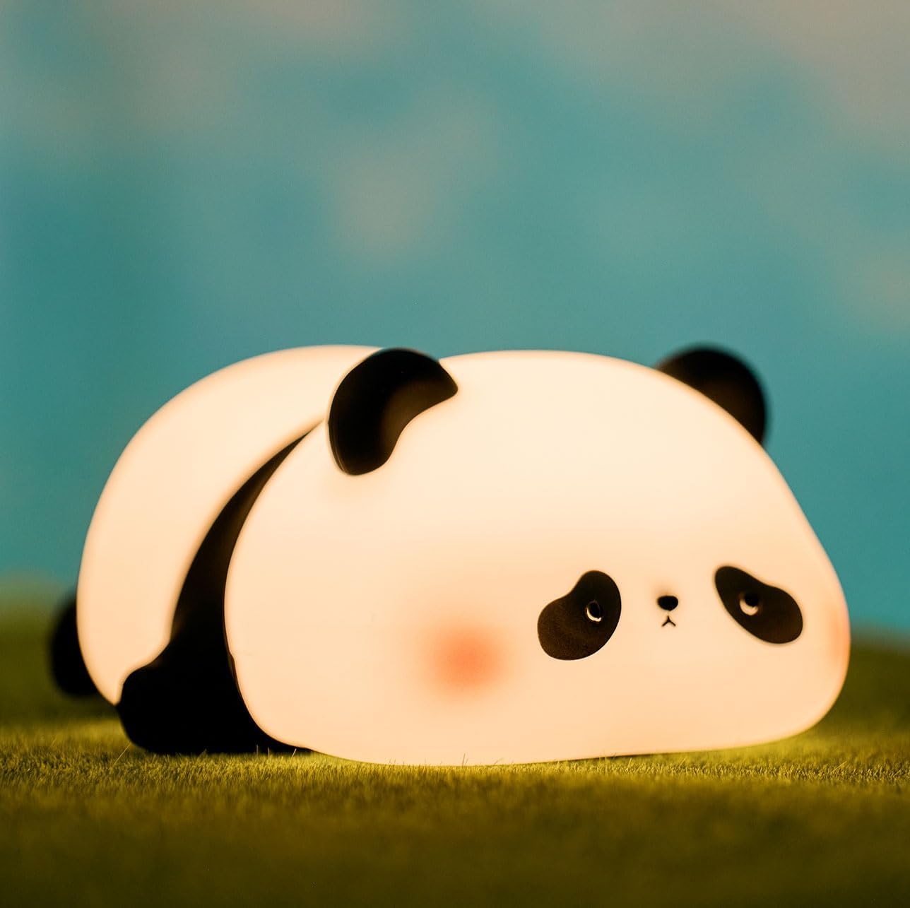 Panda-shaped night light on grass with a blurred background