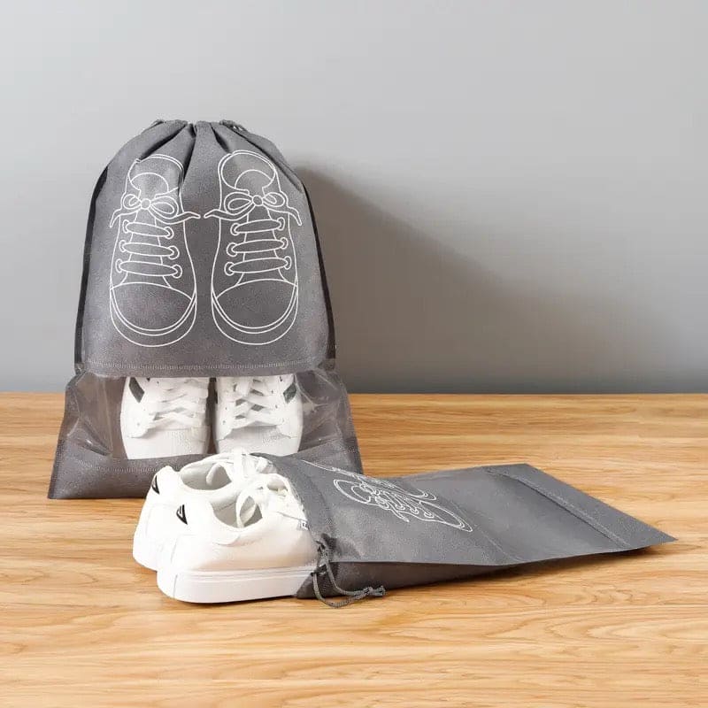 Gray drawstring shoe bags with white sneakers on a wooden surface and gray background Shoe bag