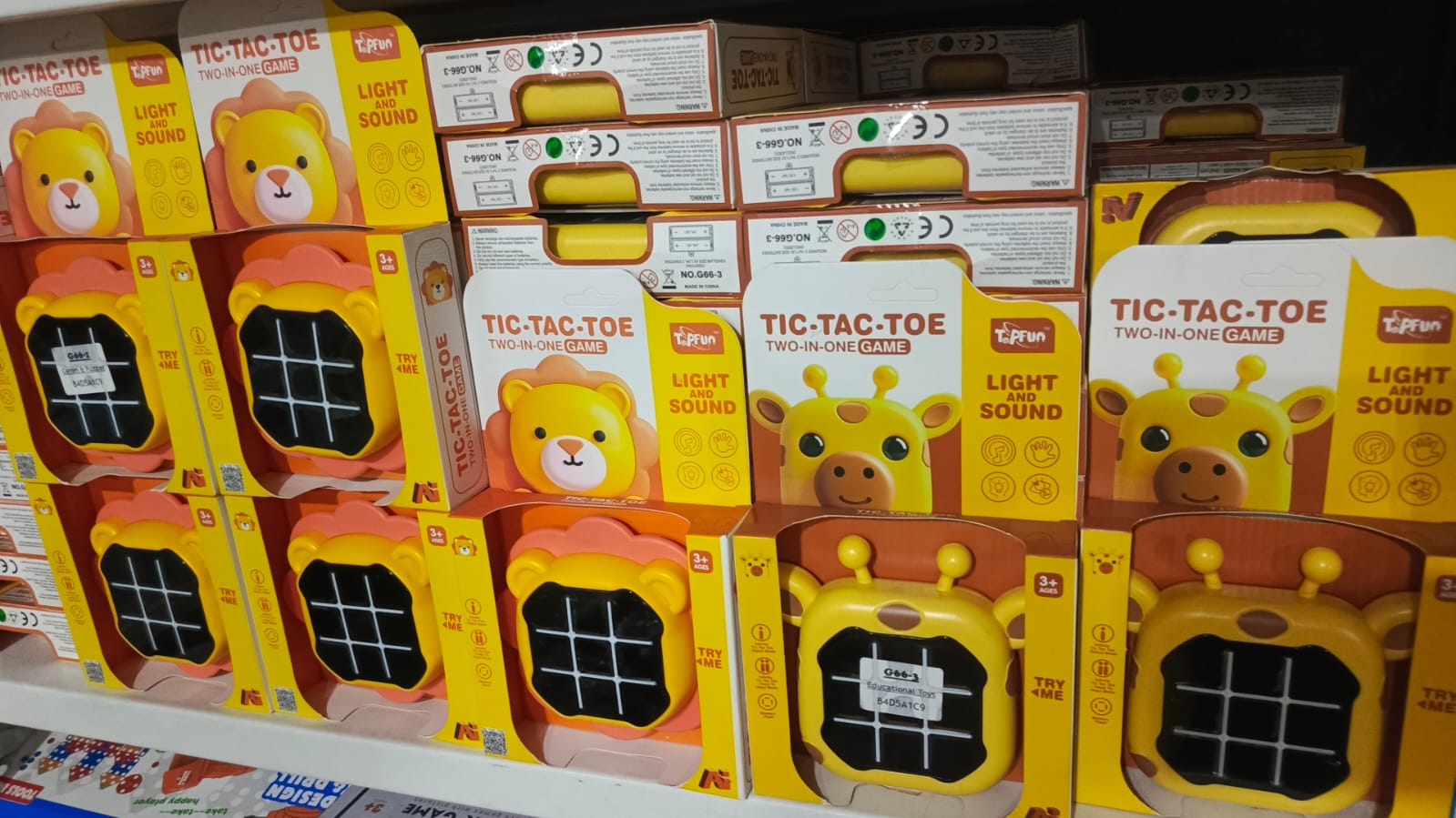 Multiple boxes of Tic-Tac-Toe games with light and sound features on a shelf.