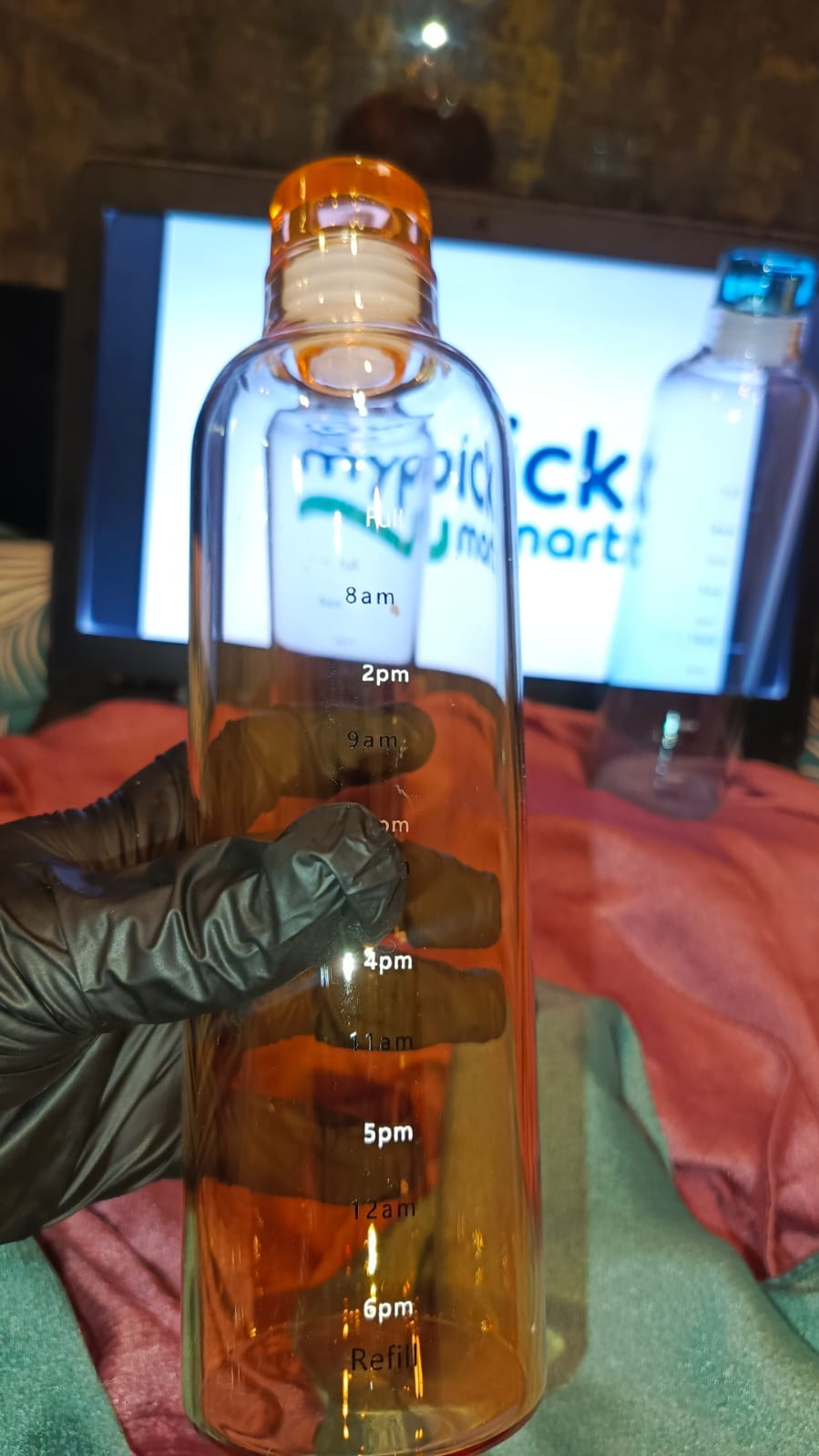 Bottle with a time indicator held by a gloved hand, with a blurred background
