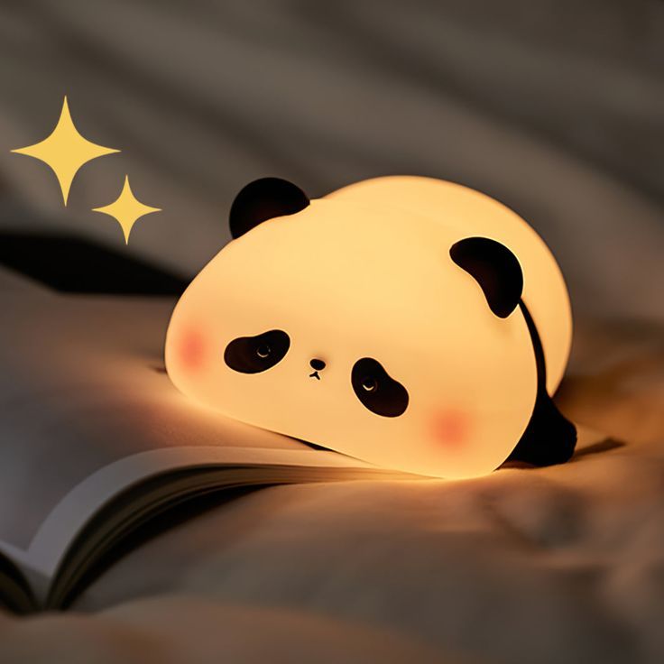 Panda-shaped night light on an open book with a dark background