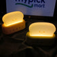 Two glowing night lights shaped like a toaster and a slice of bread on a dark surface with 'mypick mart' logo in the background.