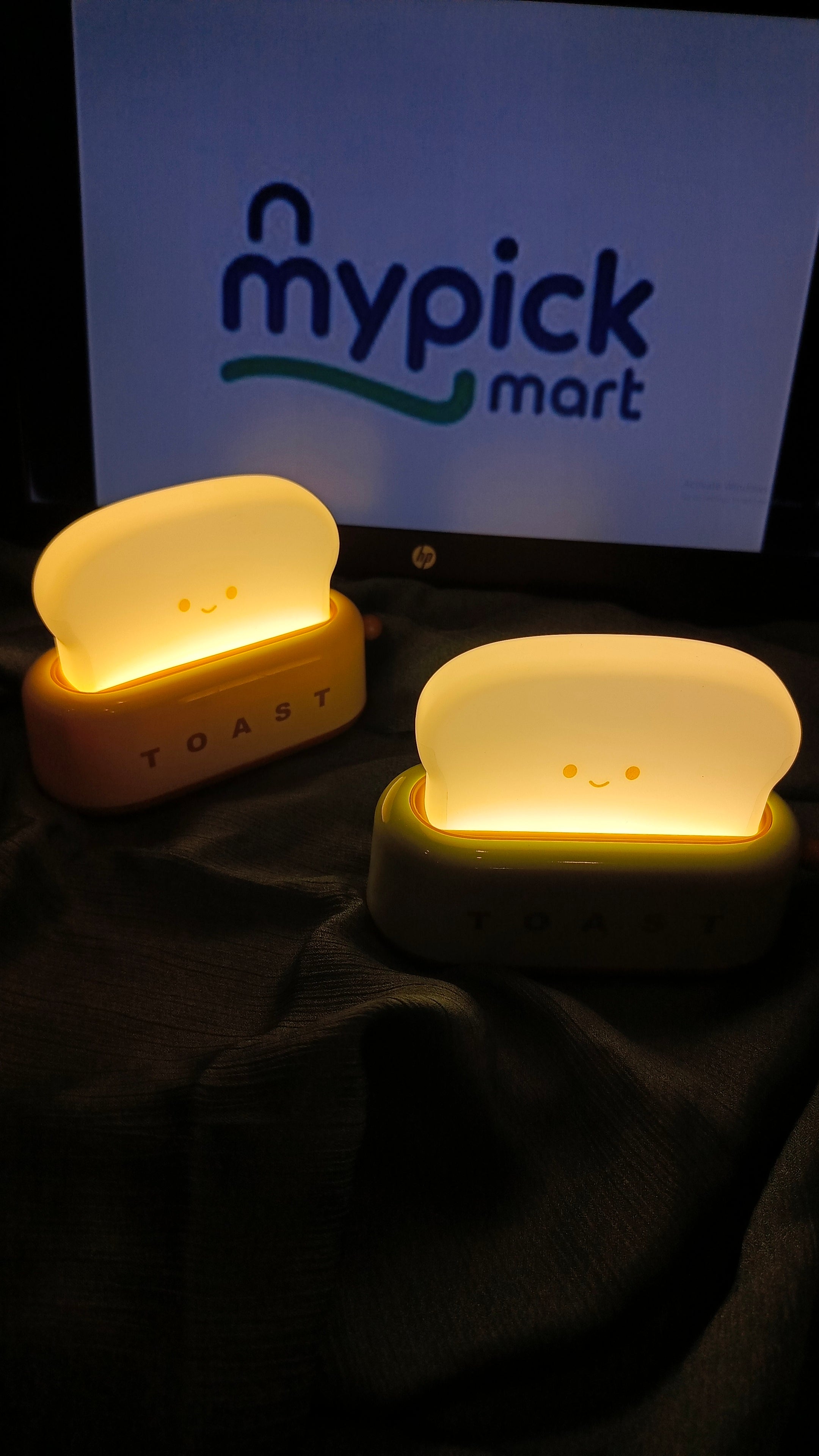 Two glowing night lights shaped like a toaster and a slice of bread on a dark surface with 'mypick mart' logo in the background.