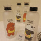 Clear water bottles with bear illustrations and 'WEBABE BEARS' text on a tiled wall background.