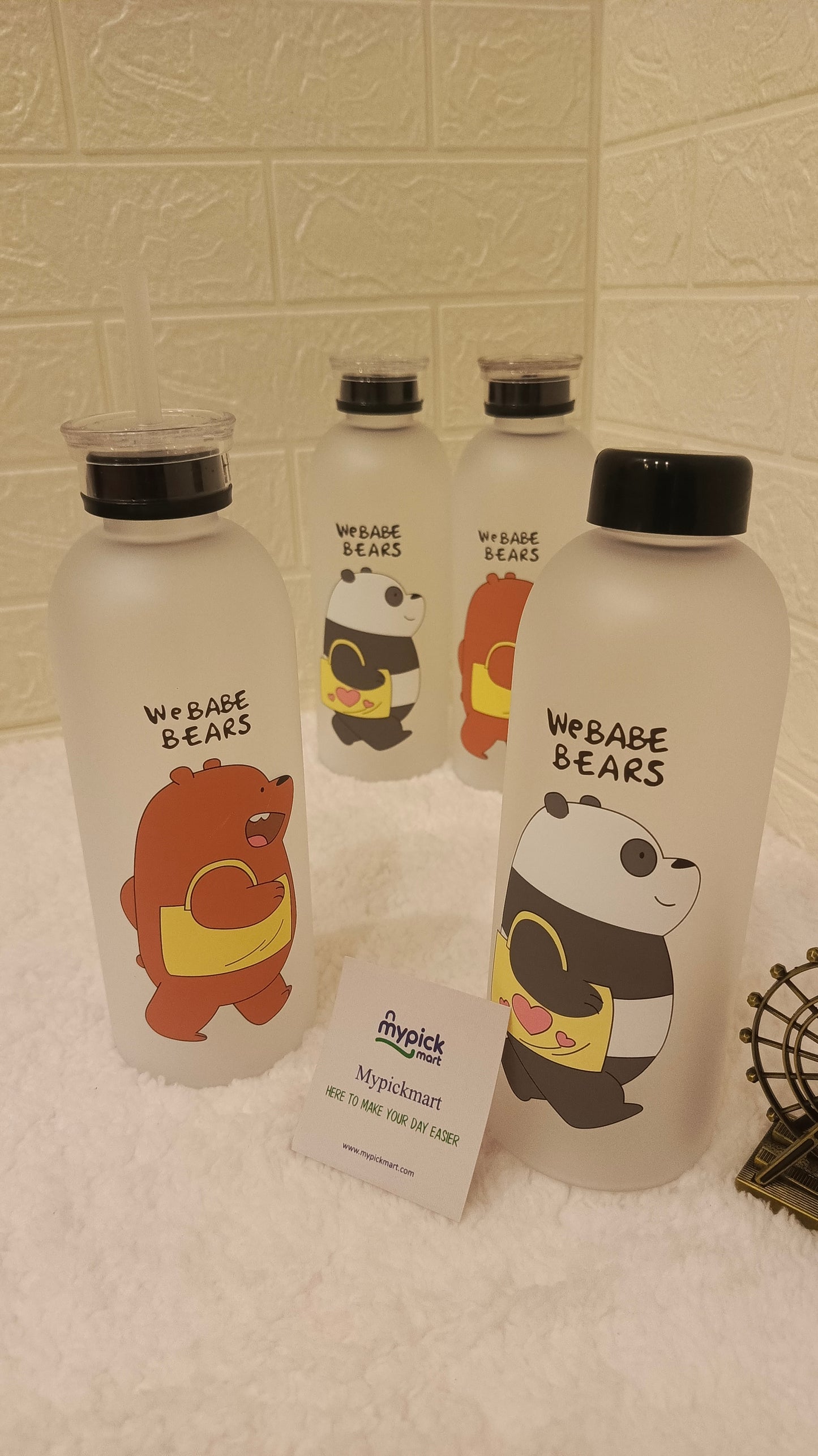 Clear water bottles with bear illustrations and 'WEBABE BEARS' text on a tiled wall background.