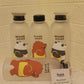 Three bottles with bear-themed labels on a textured wall background