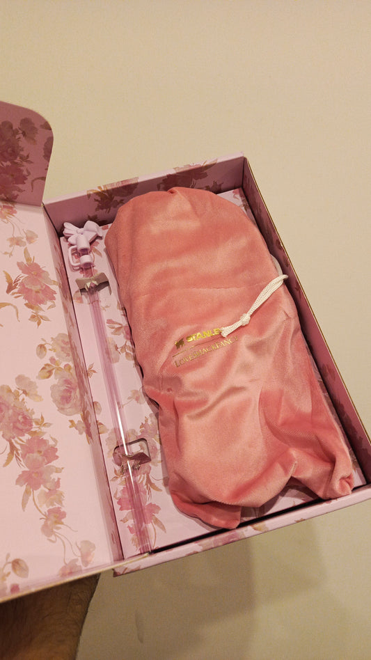 Pink satin eye mask in a decorative box on a light green surface