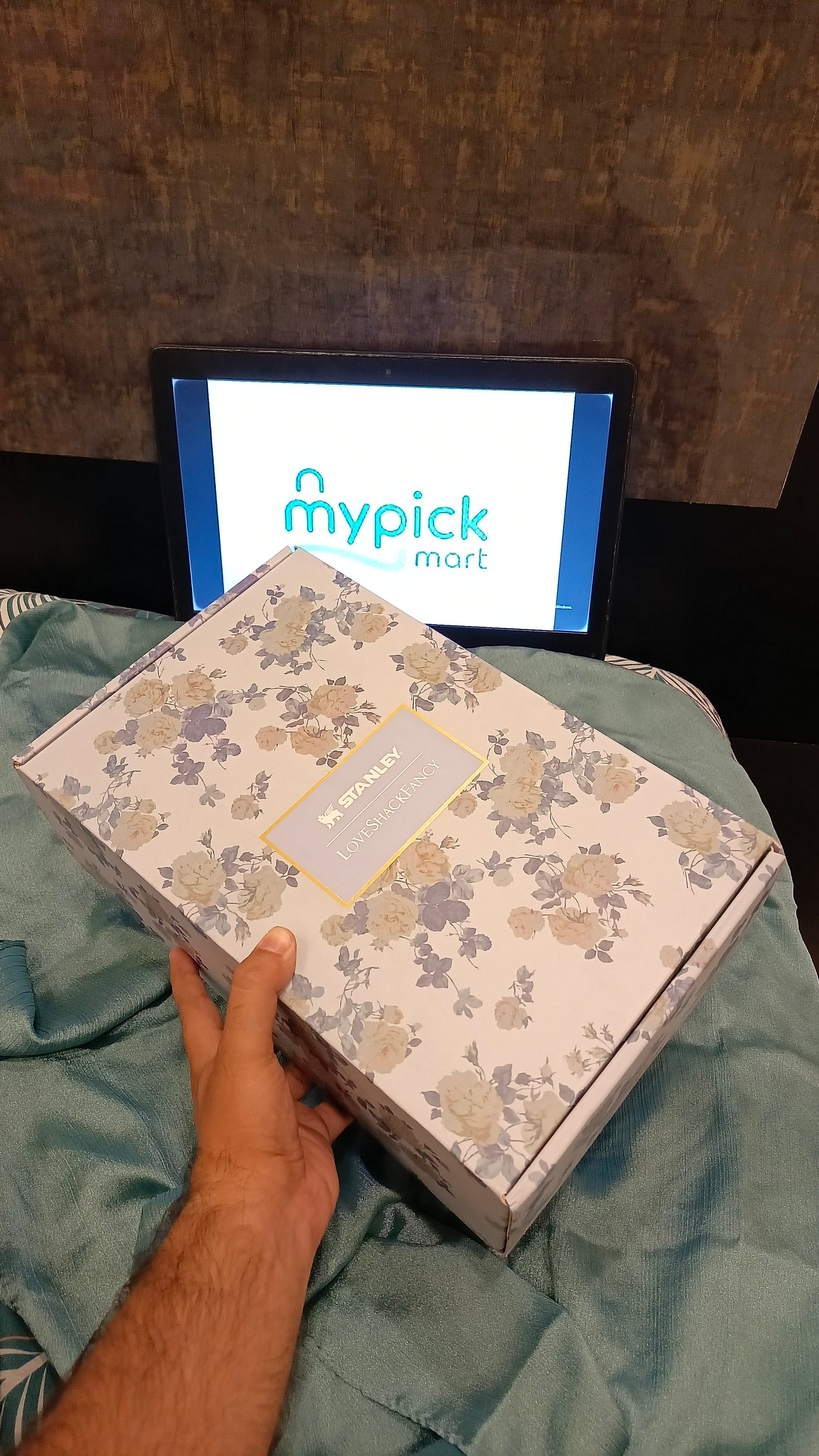 Floral-patterned box held by a hand with 'mypick mart' screen in the background