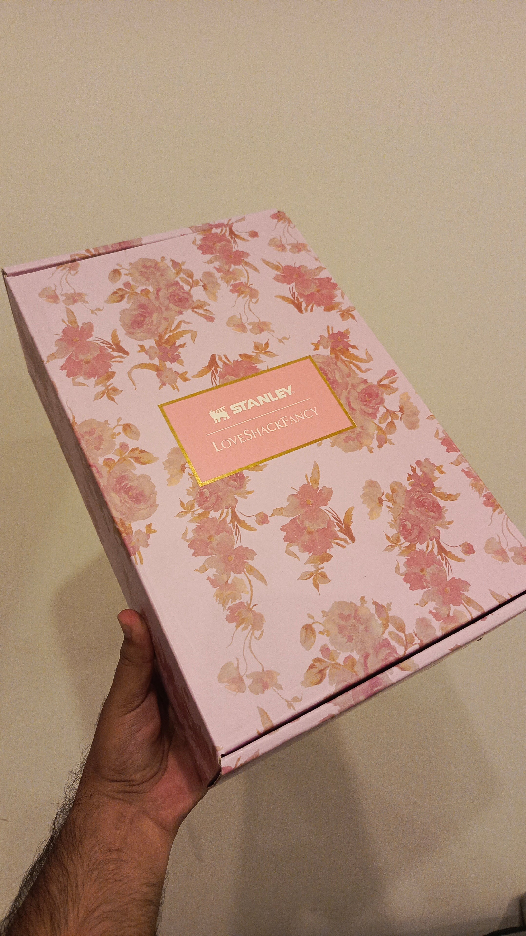 Floral-patterned box held by a hand against a plain background